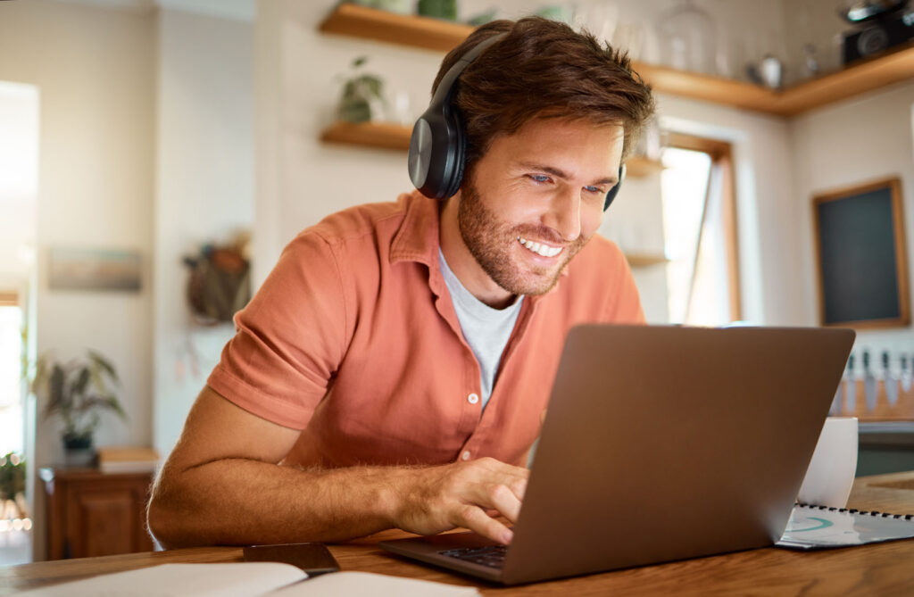 Headphones, laptop and remote work, happy man in kitchen on vide