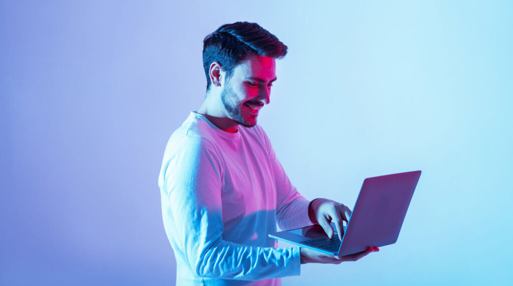 Work and play online. Happy guy holding laptop and typing