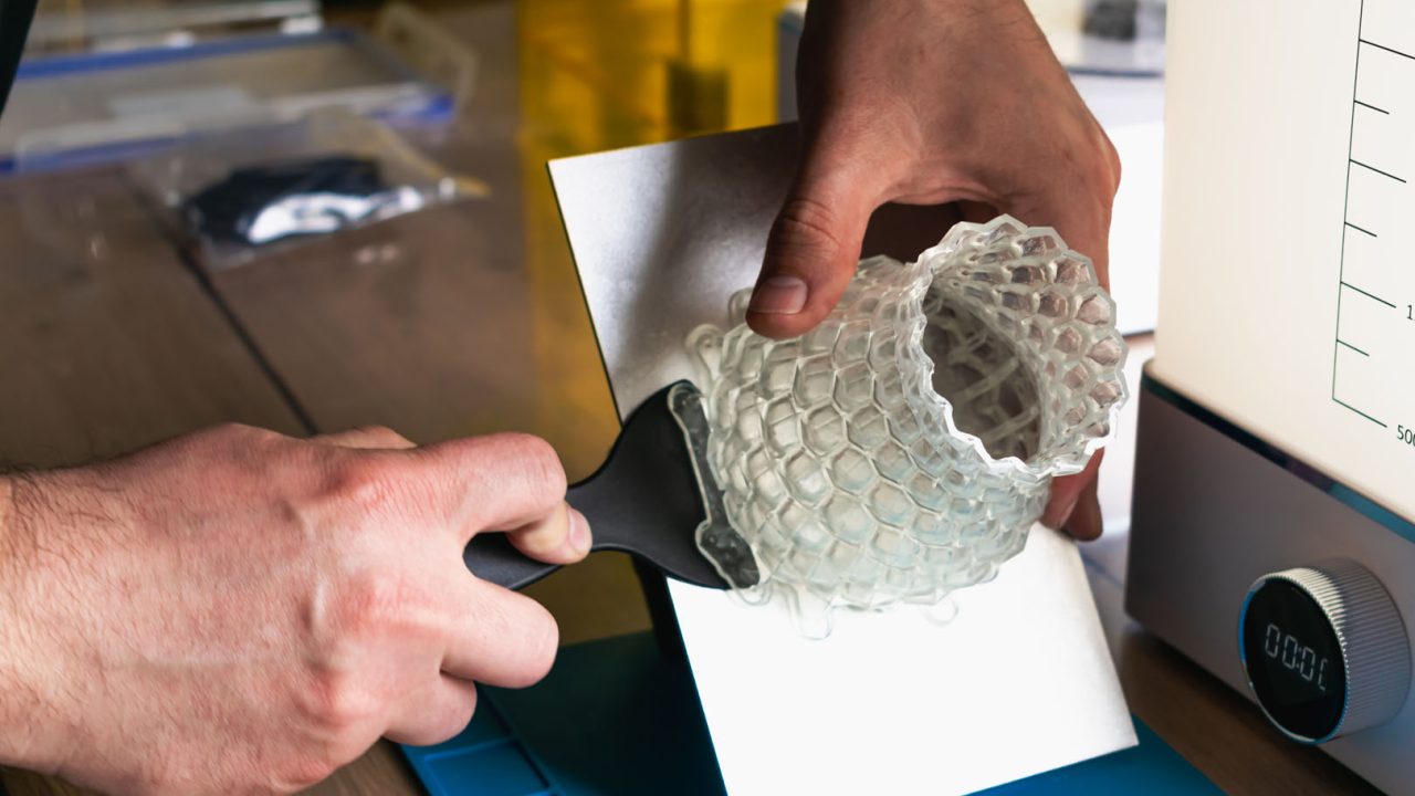 Man holding a 3d resin object with next to him wash and cure mac