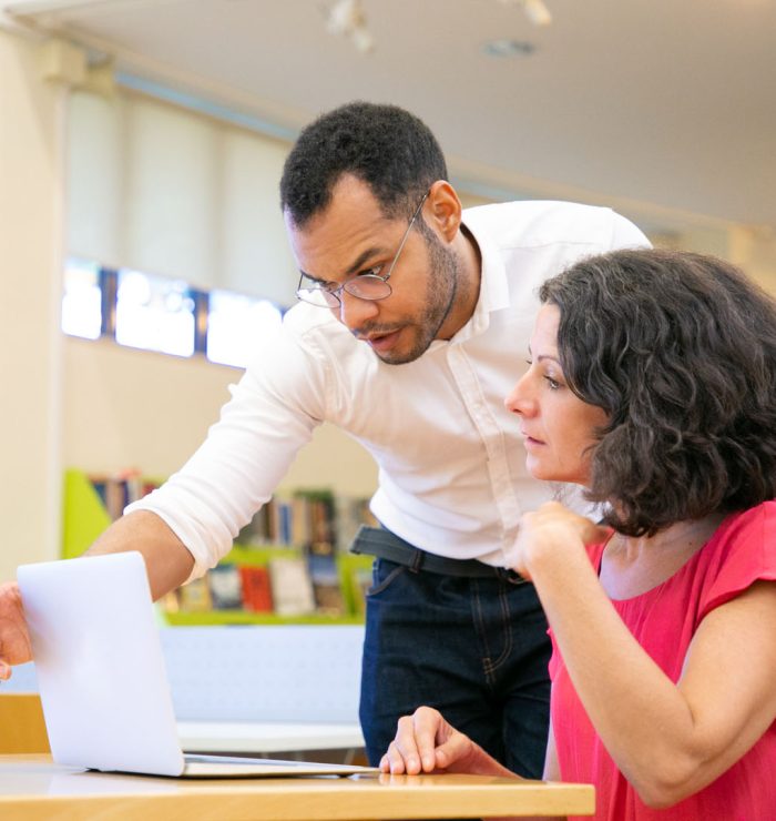 Instructor checking student work in library