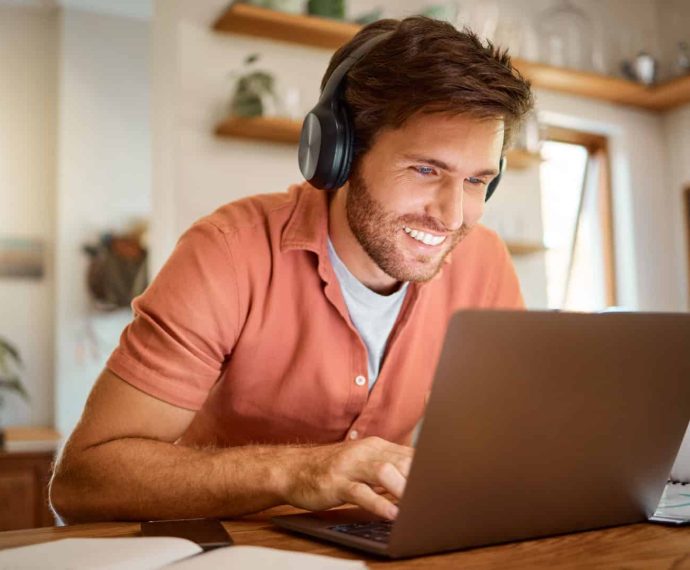 Headphones, laptop and remote work, happy man in kitchen on vide