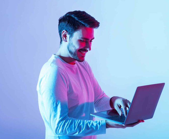 Work and play online. Happy guy holding laptop and typing