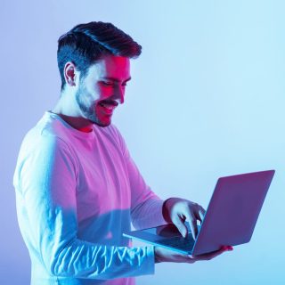 Work and play online. Happy guy holding laptop and typing