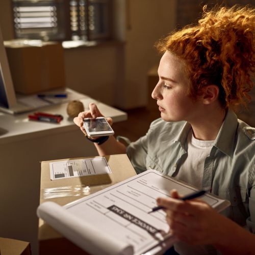 Yung woman preparing packages for delivery and scanning bar code