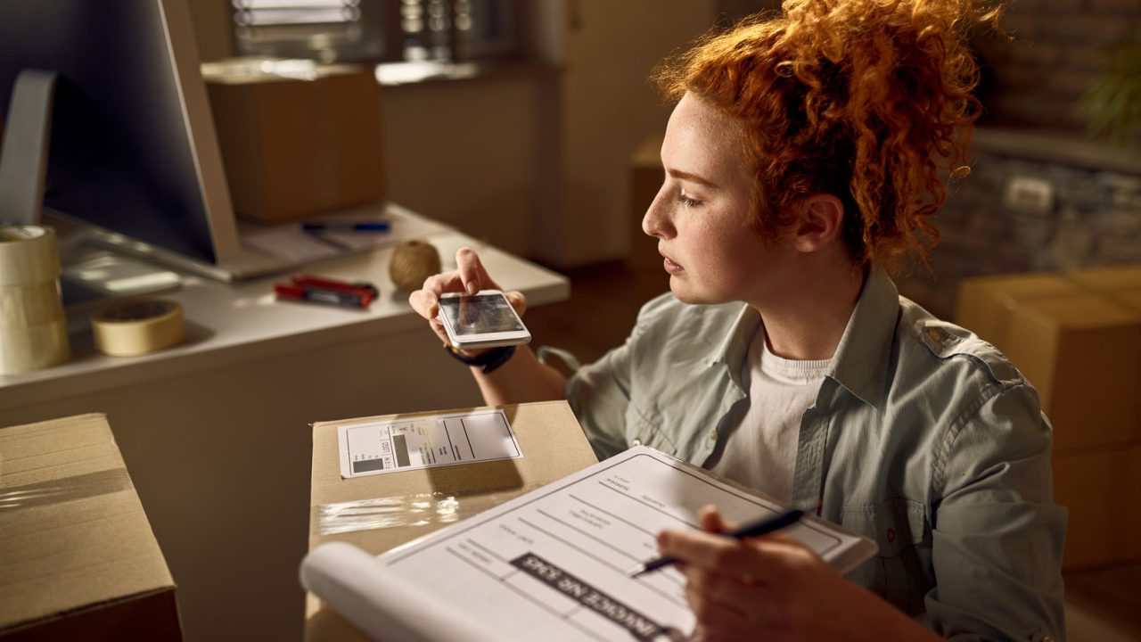 Yung woman preparing packages for delivery and scanning bar code