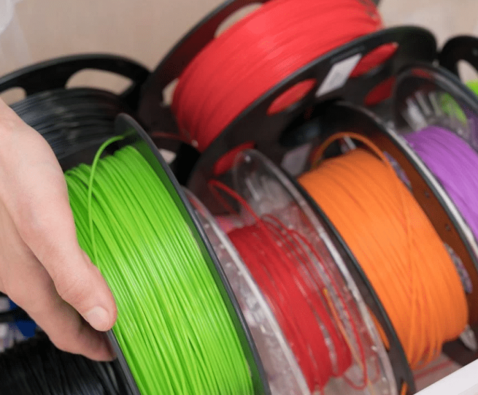 Main qui tient une bobine de filament PLA pour impression 3D